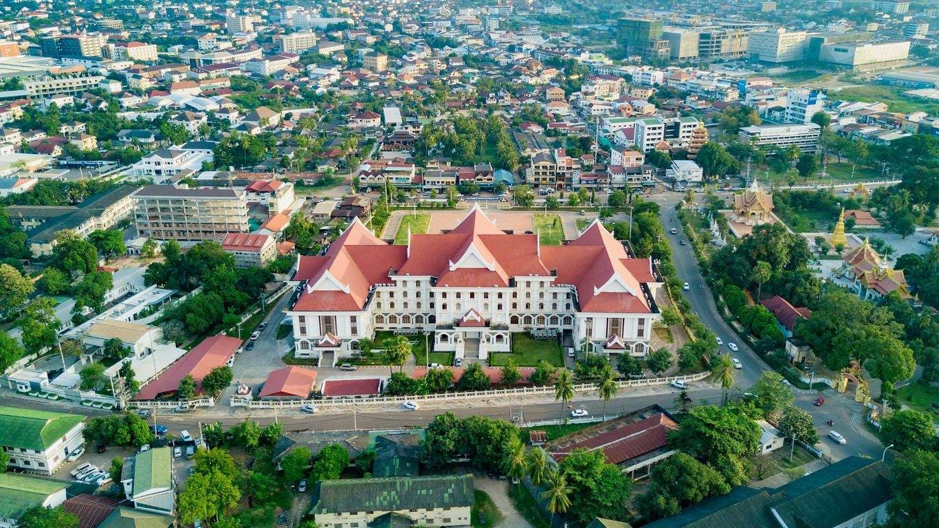 Aerial view of the Royal Palace of Thakhèk, featuring traditional Lao architecture with red roofs amidst the city center.