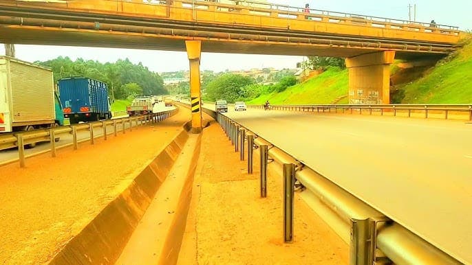 Wide view of a bypass highway under an overpass with trucks and cars, matching the Bweyogerere traffic scene intent.