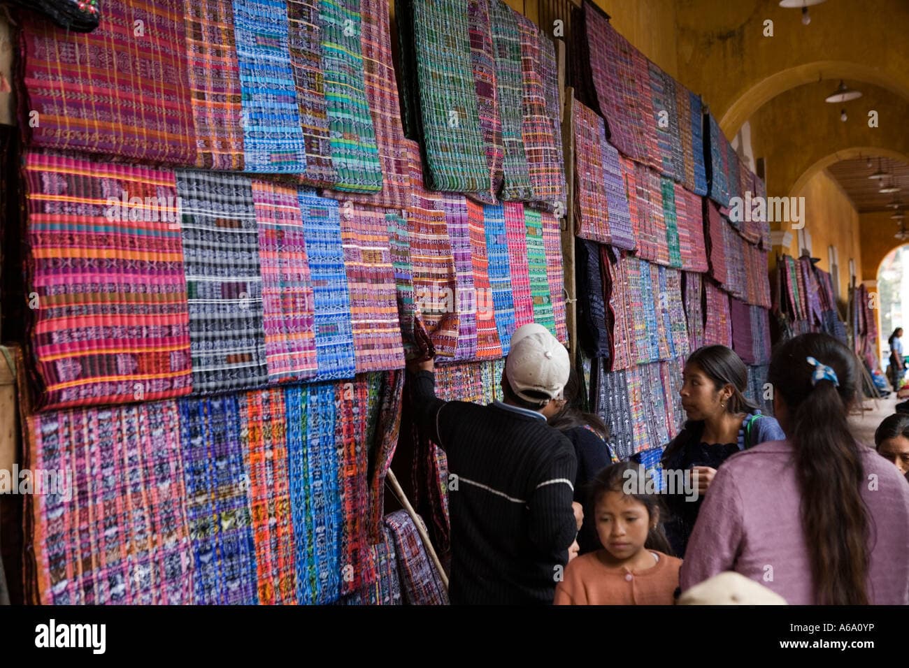 Outdoor artisan market in Guatemala featuring colorful woven rugs and textiles for sale