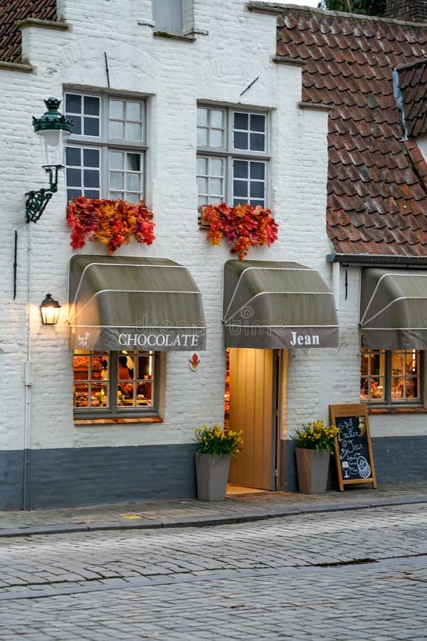 Historic whitewashed shop facade on a cobblestone street in a Belgian town