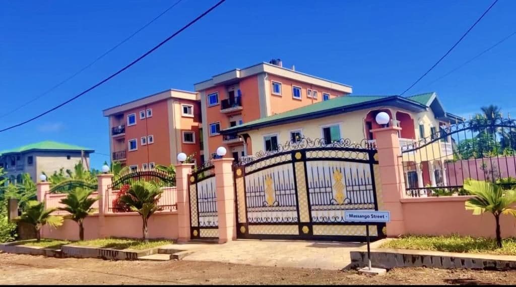Residential buildings with a gated entrance and a street sign reading Massango Street in Limbe, Cameroon, under a clear blue sky