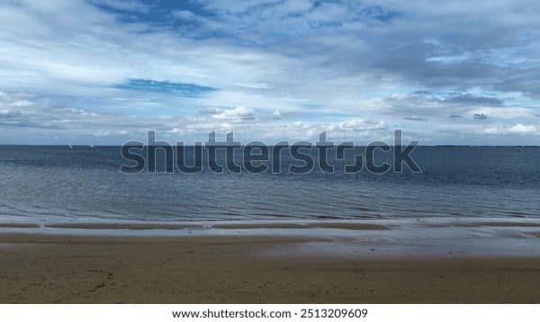 Wide coastal landscape of a Dutch beach with calm sea and overcast sky, representative of the Netherlands