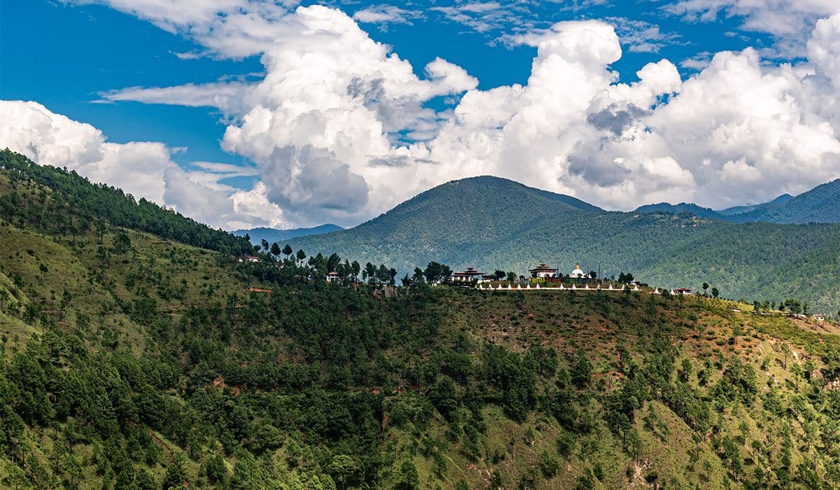 Green mountain ridge with traditional buildings and stupa in Bhutan