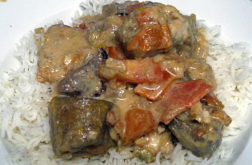 A close-up shot of a traditional Comorian meal featuring chunks of fish and vegetables in a creamy sauce served over white rice.