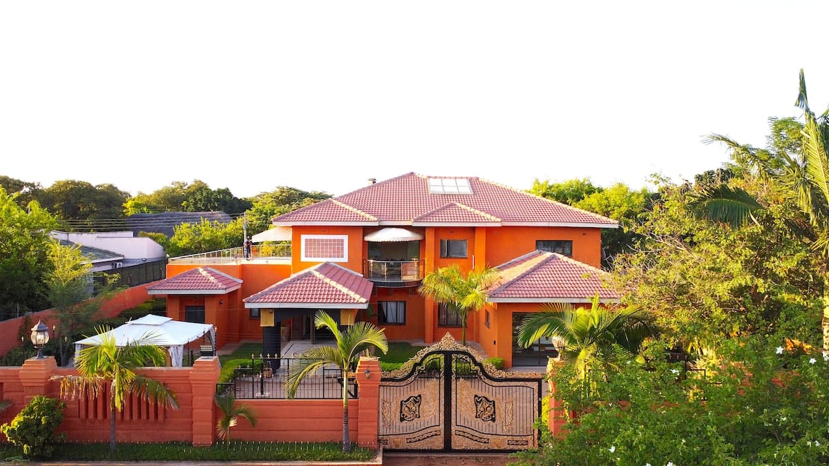 Exterior view of a guest lodge building in Zimbabwe, featuring a modern facade with large windows and a covered patio area