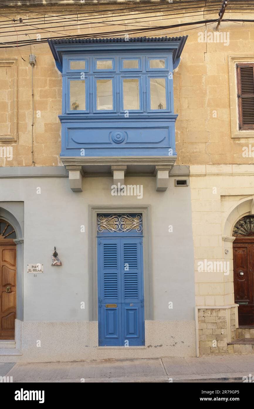 Exterior view of historic stone buildings featuring traditional blue wooden balconies (gallarija) in Paola, Malta
