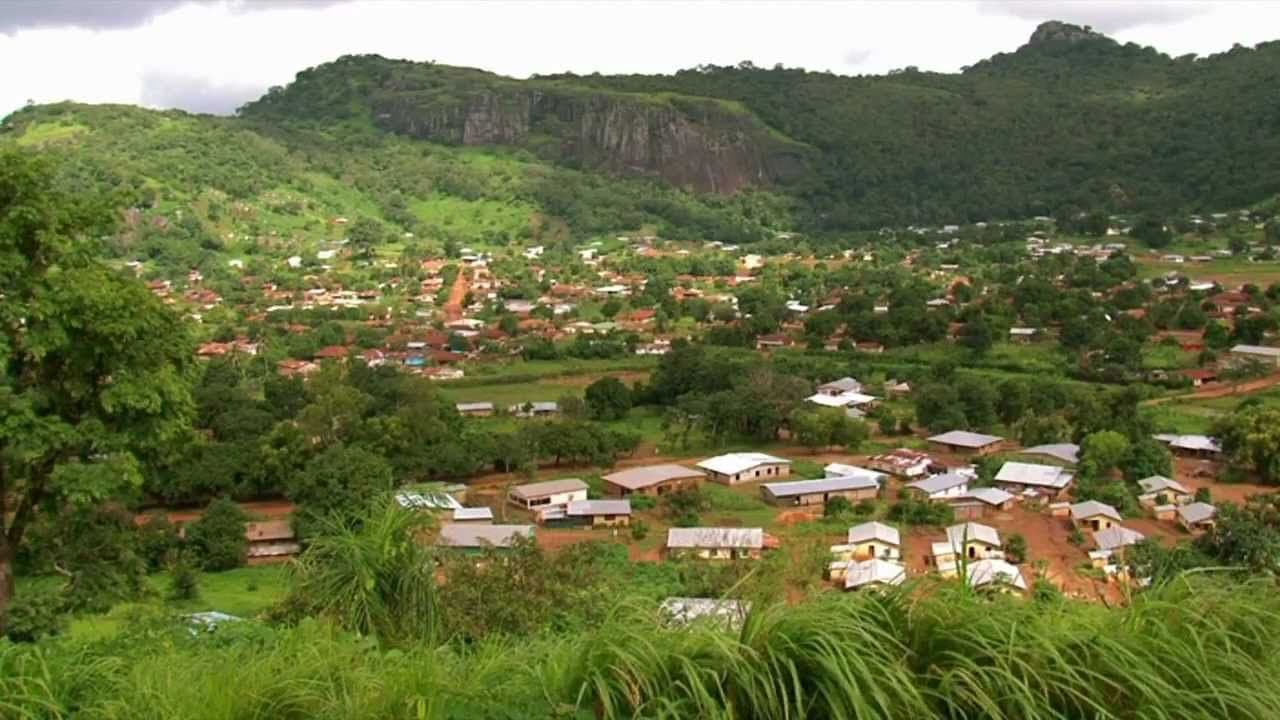 Aerial view of a rural village in Sierra Leone surrounded by dense jungle and hills.