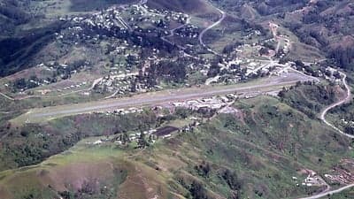 Aerial view of Chimbu Airport runway and terminal nestled in the green hills of Kundiawa, Papua New Guinea.