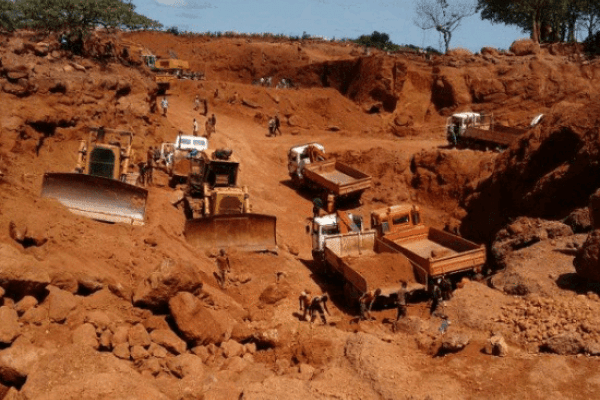 Heavy machinery and trucks on a red-earth mining site in the Lola region, Guinea
