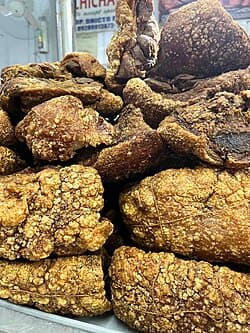 Close-up of crispy fried pork belly, known as bagnet, a traditional Ilocano delicacy, piled high at a market stall.