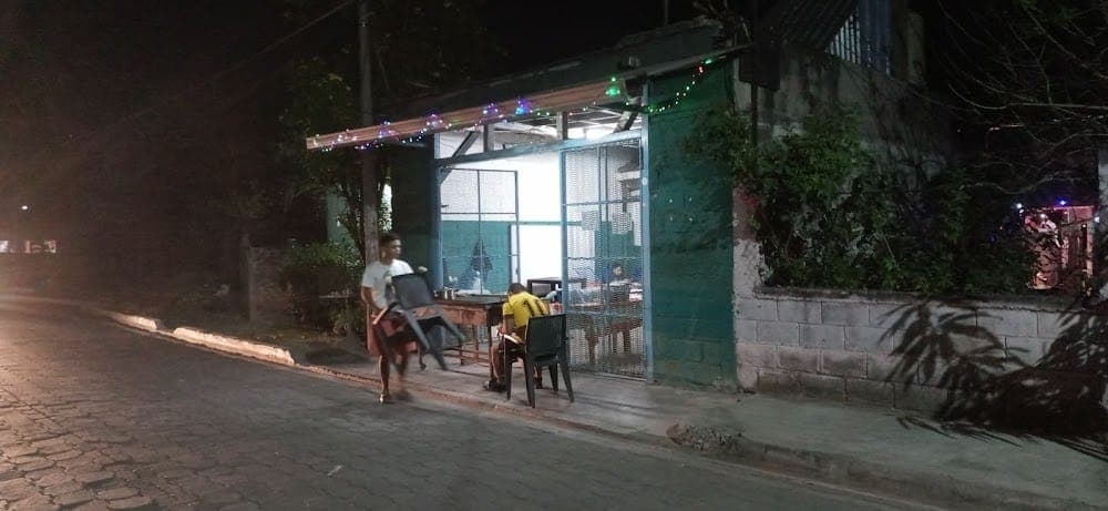 Exterior of a pupuseria in Olocuilta, El Salvador, showing traditional food stall signage at dusk