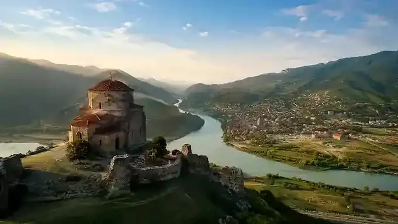 Aerial view of the Baghdati Church on a hilltop overlooking the Rioni River and surrounding valley landscape.