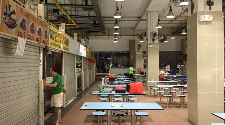 Street food stalls at a hawker center in Little India, Singapore, with vendors and food displays