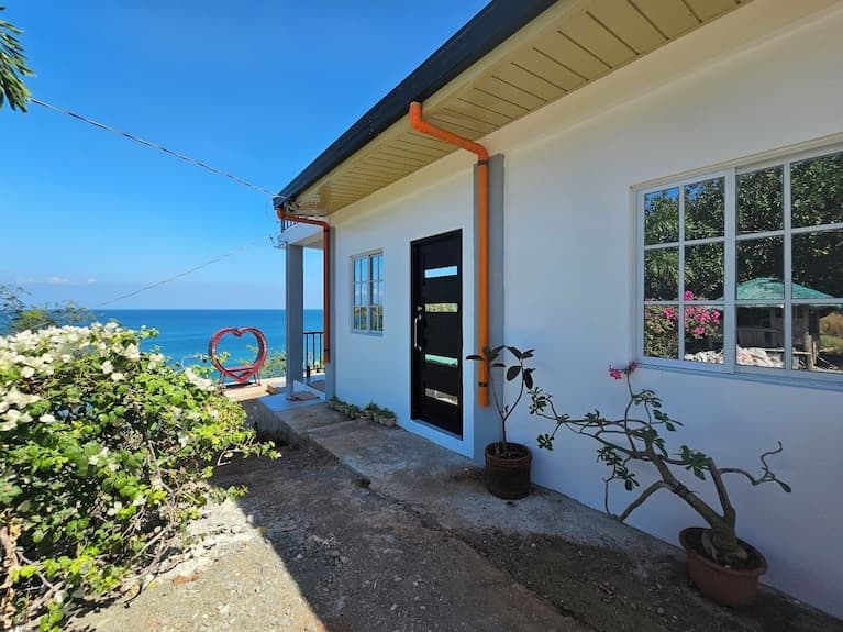 Exterior of Casa Maria guesthouse in Sison, Philippines with ocean view and tropical landscaping.
