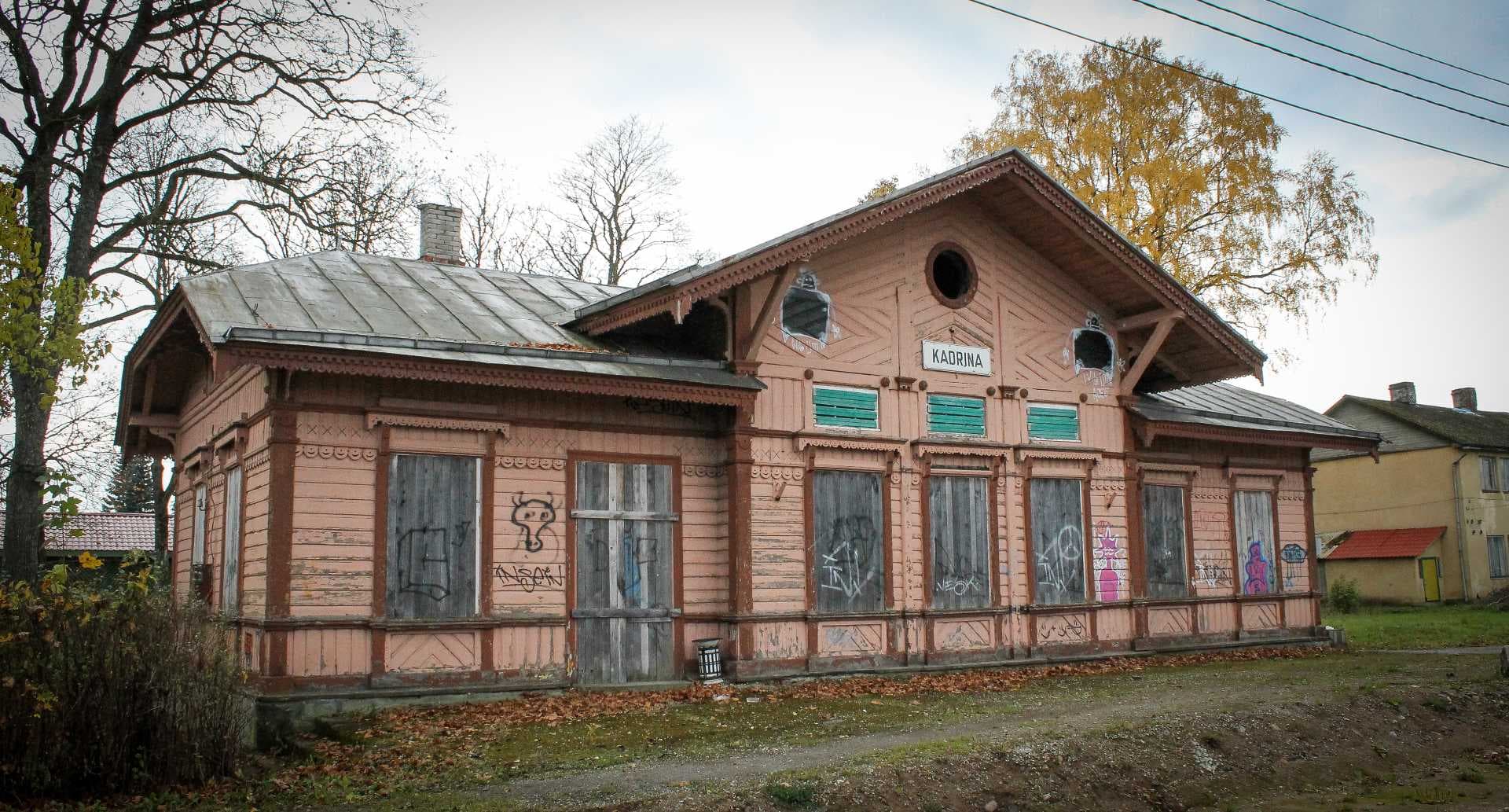 Weathered pink wooden Kadrina railway station exterior with boarded windows and a visible station sign
