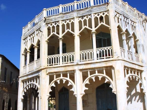 Whitewashed multi-story building with ornate arched loggias and balconies under a clear blue sky in Adi Keyh, Eritrea.