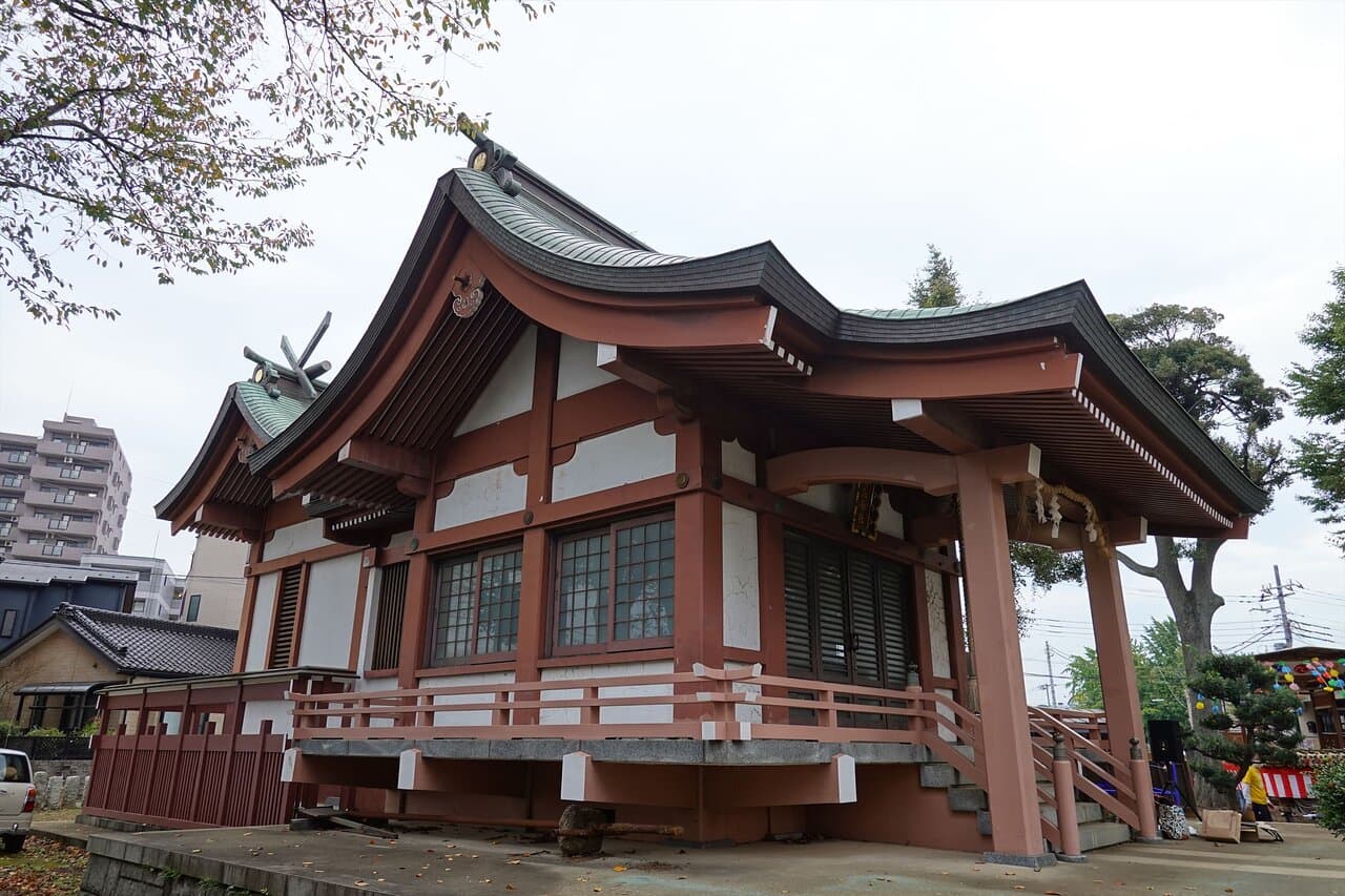 Exterior view of the Shiga Naoya Teiato historic residence, featuring traditional Japanese architecture with a curved roof and red wooden structure.
