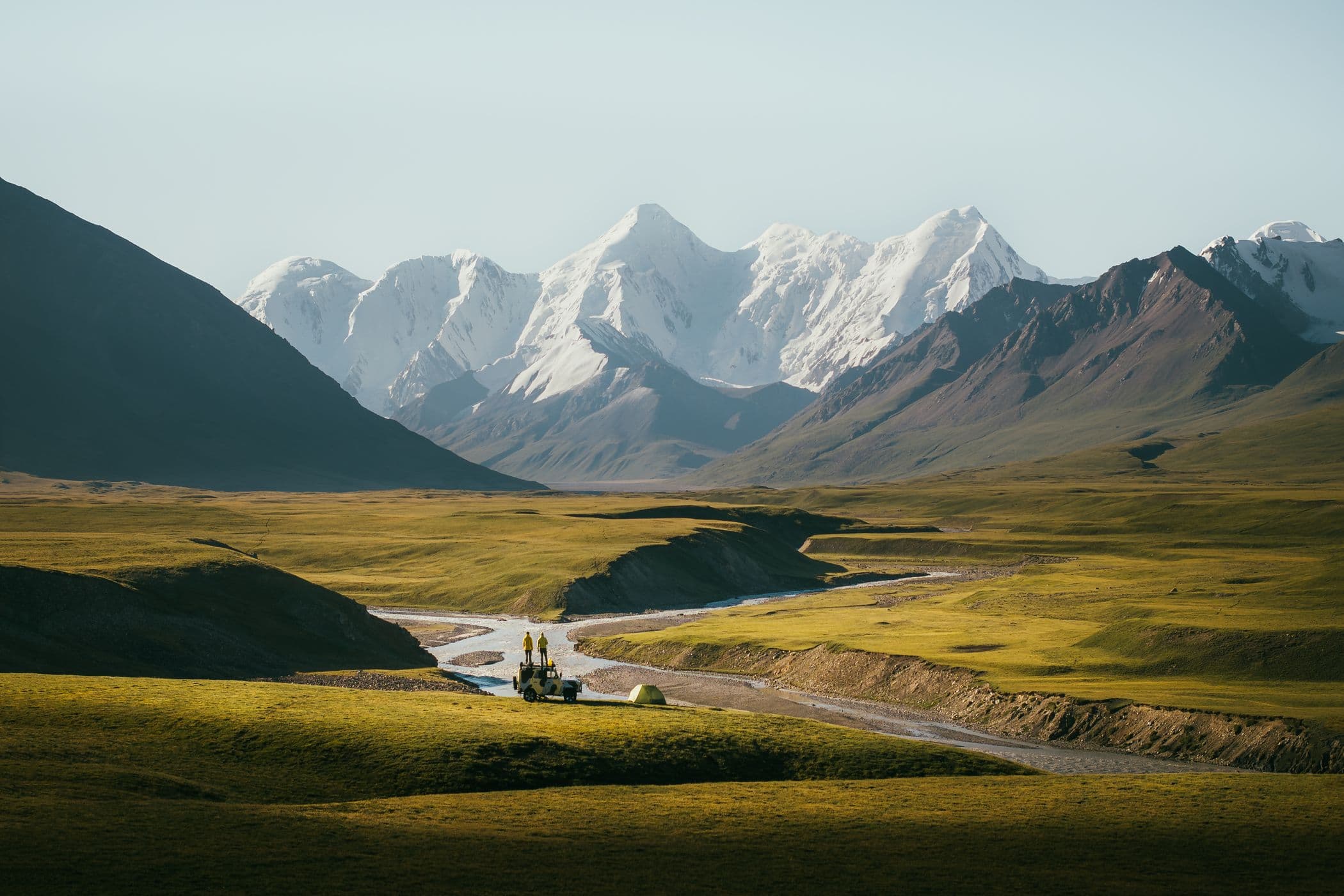 Scenic paved road winding through mountains in Kyrgyzstan with green slopes and blue sky