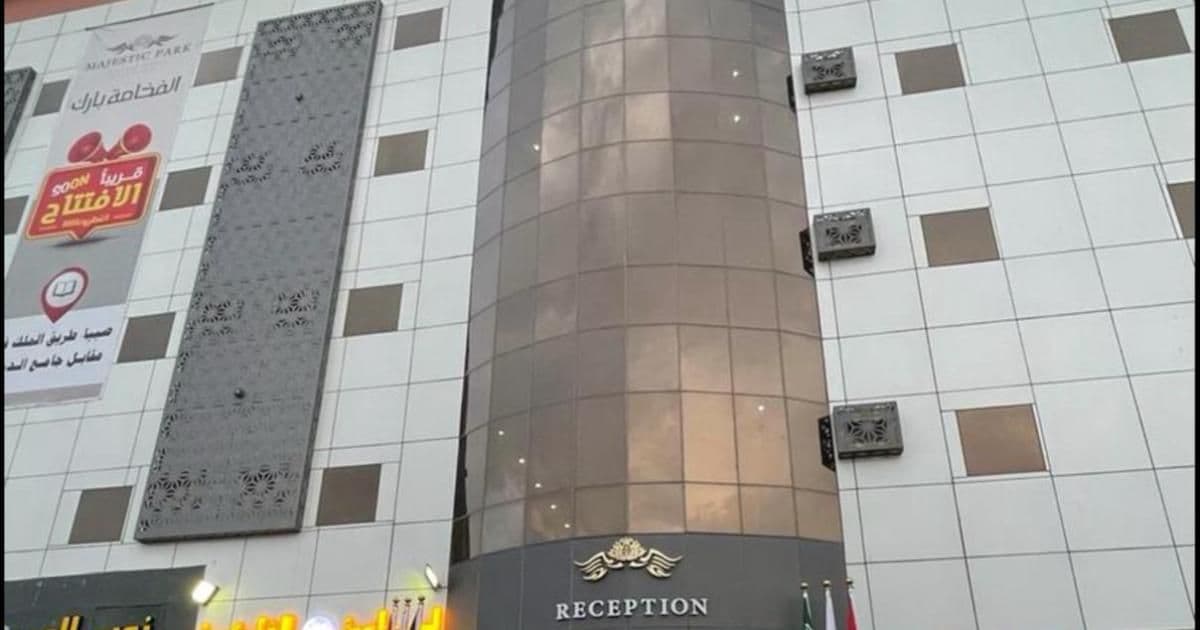 Exterior of a hotel in Şabyā with a cylindrical glass entrance and white tiled facade