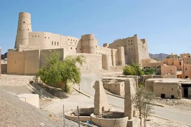 Courtyard of a traditional riad guesthouse in Bahlā’, Oman, featuring stone walls and a central garden