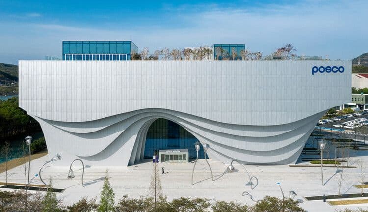 Aerial view of the modern, wave-shaped POSCO headquarters building in Gwangyang-si, featuring a large plaza and surrounding greenery