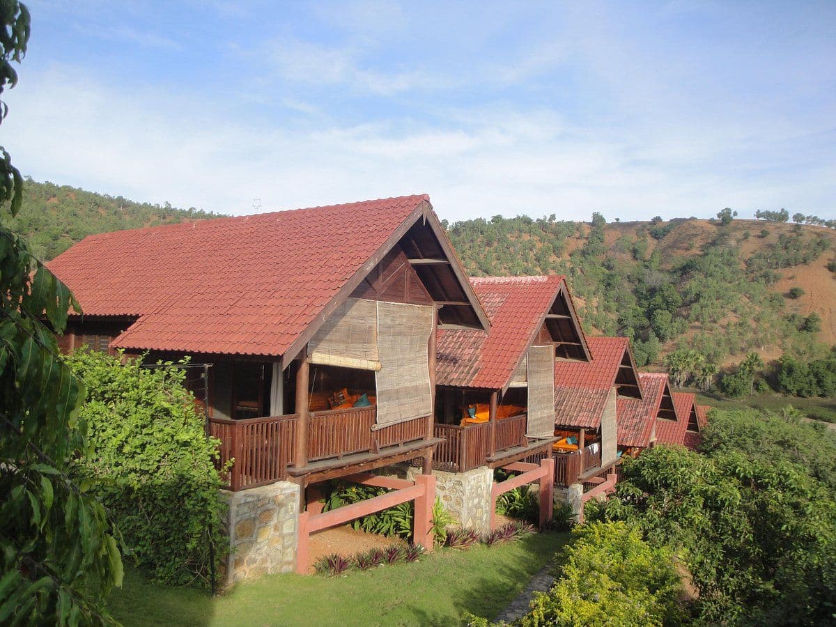 Simple stilted guest bungalows on a green highland hillside near Ermera, representative of rural homestay accommodation near Laclo.