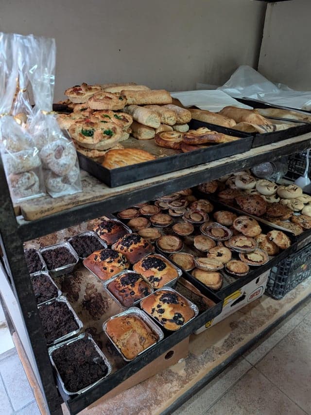 Exterior of a local bakery in Paola, Malta, with pastizzi pastries visible in the window display