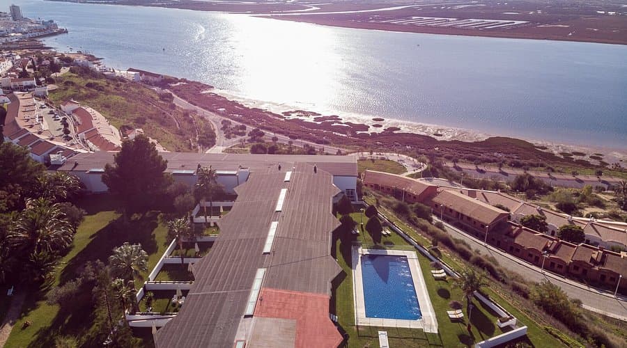 Sandy beach with sunshades and blue chairs at Playa de Ayamonte, Spain, near the Parador de Ayamonte hotel