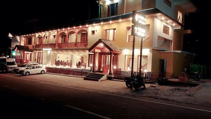 Exterior view of a lodging property in Chamoli district, India, at night, highlighting the building facade and street-level accessibility.