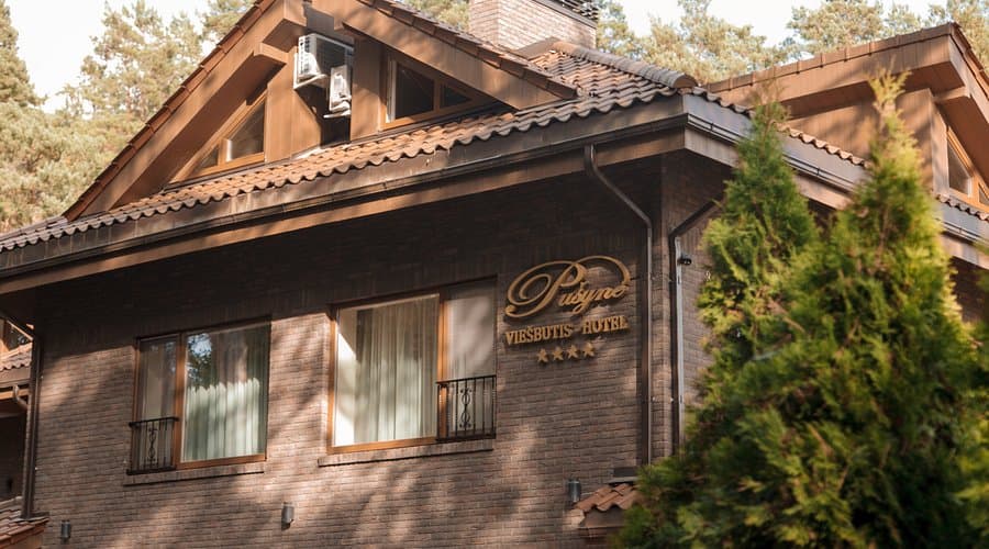 Wood-paneled exterior of a traditional Lithuanian spa hotel in Birštonas, with large windows and ornate trim
