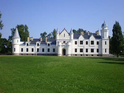 White castle-like building with turrets and a clock tower on a lawn in Kadrina, Estonia