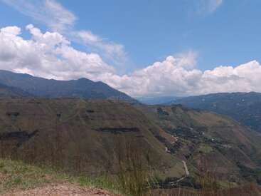 Green mountain valley near Liborina with rolling hills, distant peaks, and a partly cloudy blue sky.